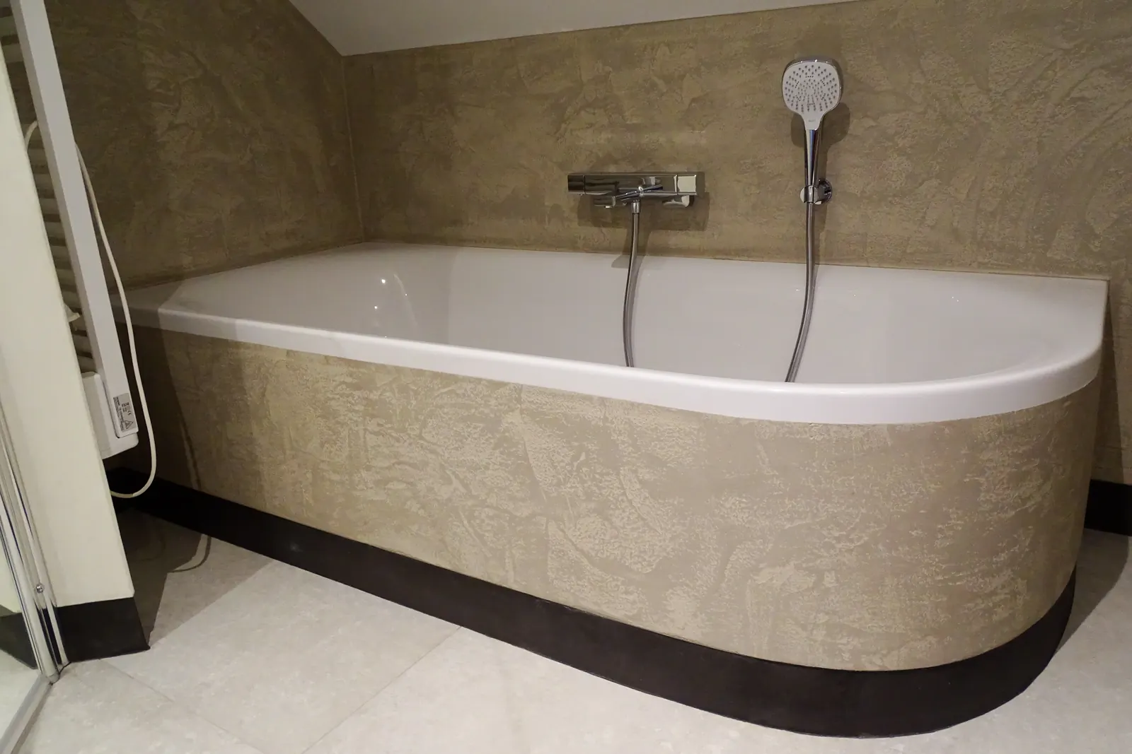 Badkamer met bad en een zandkleurige ombouw van designpleister