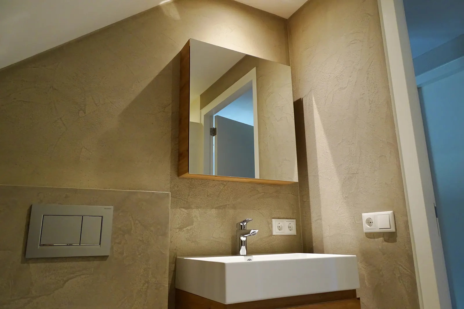 Badkamer met marmerachtige designpleister, wastafel en spiegelkast